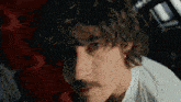 a close up of a man 's face with curly hair and a mustache
