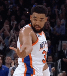 a basketball player wearing a new york knicks jersey is giving a thumbs up .