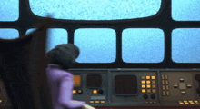 a woman in a purple shirt sits at a control panel