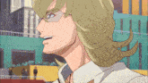 a man with blonde hair and glasses is smiling in front of a green building