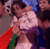 a man in a white shirt is being held by a crowd