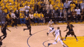 a group of basketball players are playing a game on a court with a crowd watching .
