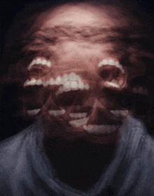 a blurry picture of a man 's face with his mouth open and teeth showing .