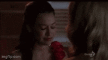 two women are standing next to each other and one is crying while the other is holding a rose .
