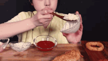 a woman is eating a bowl of yogurt with a wooden spoon