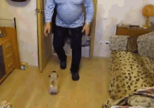 a man in a striped shirt is walking with a bottle of water on the floor