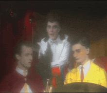 a man in a white shirt and tie stands next to a man in a yellow jacket