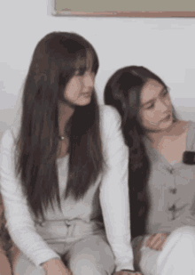 two women are sitting next to each other on a couch and one of them is looking at the camera .
