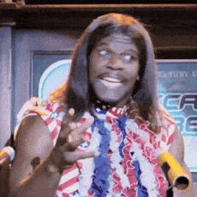 a man with long hair and a red white and blue shirt is holding a microphone