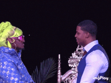 a man and a woman are standing next to each other and the man is holding a saxophone in his hand