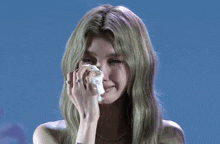a woman with green hair is crying while holding a napkin to her face .
