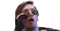 a man is holding a pair of sunglasses over his mouth