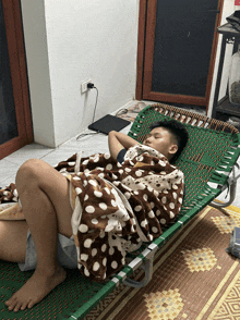 a young boy is laying on a green folding bed with a polka dot blanket