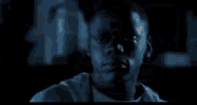 a man in a white hoodie is standing next to another man in a dark room .
