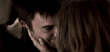 a woman is touching a man 's face while they are looking into each other 's eyes .
