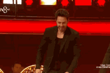 a man in a suit is applauding on a stage in front of a tv8 logo