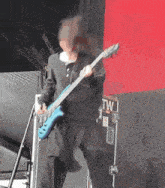 a man is playing a blue guitar in front of a tw sign