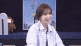 a woman in a striped shirt is smiling in front of a poster that says ' a ' on it .