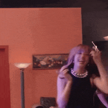 a woman in a black dress is dancing in a room with purple lights