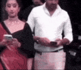 a man in a white shirt and a woman in a red dress are standing next to each other .