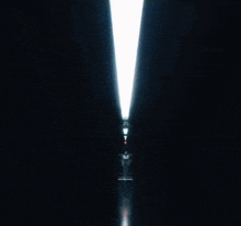 a man in a leather jacket and tie is standing in a dark room