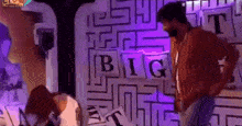 a man and woman are standing in front of a wall that says big