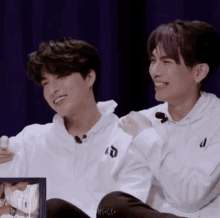 two boys are sitting next to each other and smiling .