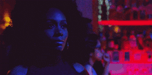 a woman with curly hair is standing in a dark room with a blue light behind her