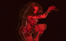 a naked woman in a red dress is dancing in the dark