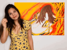 a woman in a yellow dress stands in front of a painting of a woman