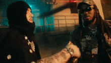 two men are shaking hands in a dark room .