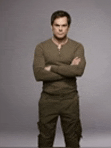 a man is standing with his arms crossed in front of a grey background .