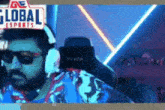 a man wearing headphones and sunglasses is sitting in front of a global esports sign