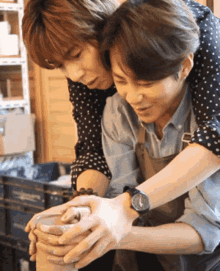 a man wearing a watch is holding another man 's shoulder