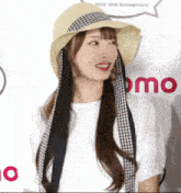 a woman wearing a hat stands in front of a sign that says omo