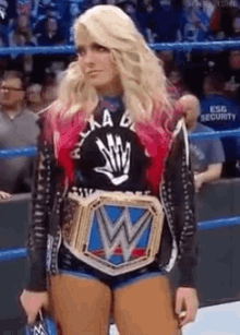 a woman is standing in a wrestling ring wearing a wwe belt .