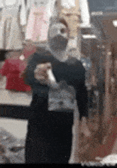 a man wearing a mask is standing in front of a mirror in a store holding a bag .