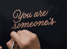 someone is writing " you are someone 's a " on a black background