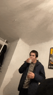 a man in a blue jacket drinks from a cup