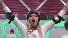 a woman wearing a helmet and knee pads with her arms in the air .