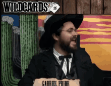 a man in a cowboy hat and bow tie stands in front of a sign that says wildcards