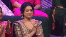 a woman is clapping her hands while sitting on a couch