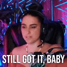 a woman wearing headphones is sitting in a chair with the words `` still got it baby '' .