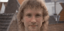 a close up of a man 's face smiling in front of a building .