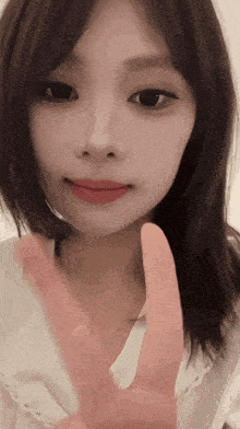 a woman with dark hair and red lips is making a peace sign with her fingers