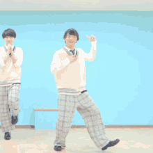 two young men in plaid pants and vests are dancing
