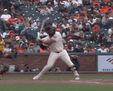 a baseball player swings his bat at a ball in front of a crowd that is watching