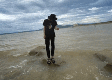 a person standing on a rock in the water wearing a t-shirt that says ' snoopy ' on it