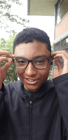 a young boy wearing glasses and a black jacket