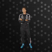 a man in a mercedes racing suit stands in front of a black background